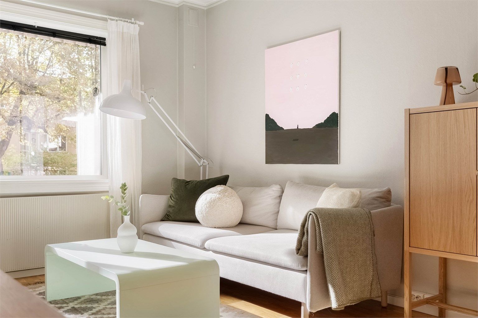 Store vindusflater fyller stuen med dagslys, og varm parkett og lyse, stilrene toner skaper en lun og harmonisk atmosfære.