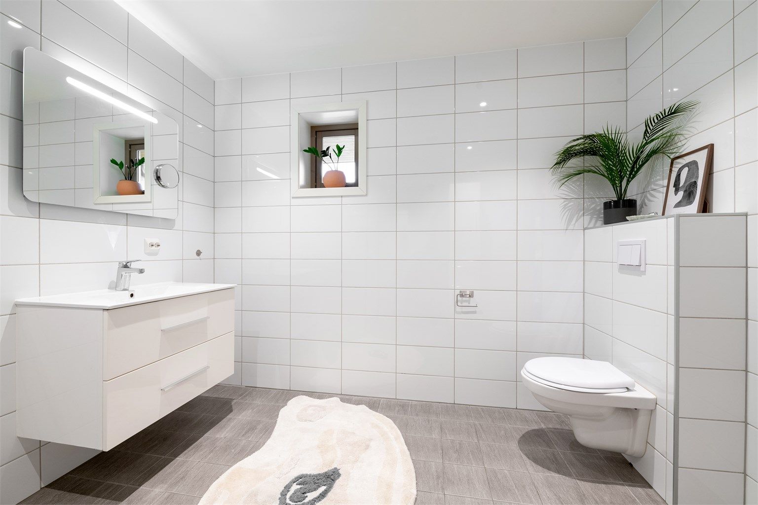 Badet er utstyrt med vegghengt toalett og servantinnredning.