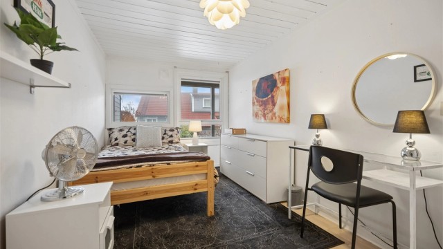 Romslig soverom med plass til stor seng, pult og oppbevaring.