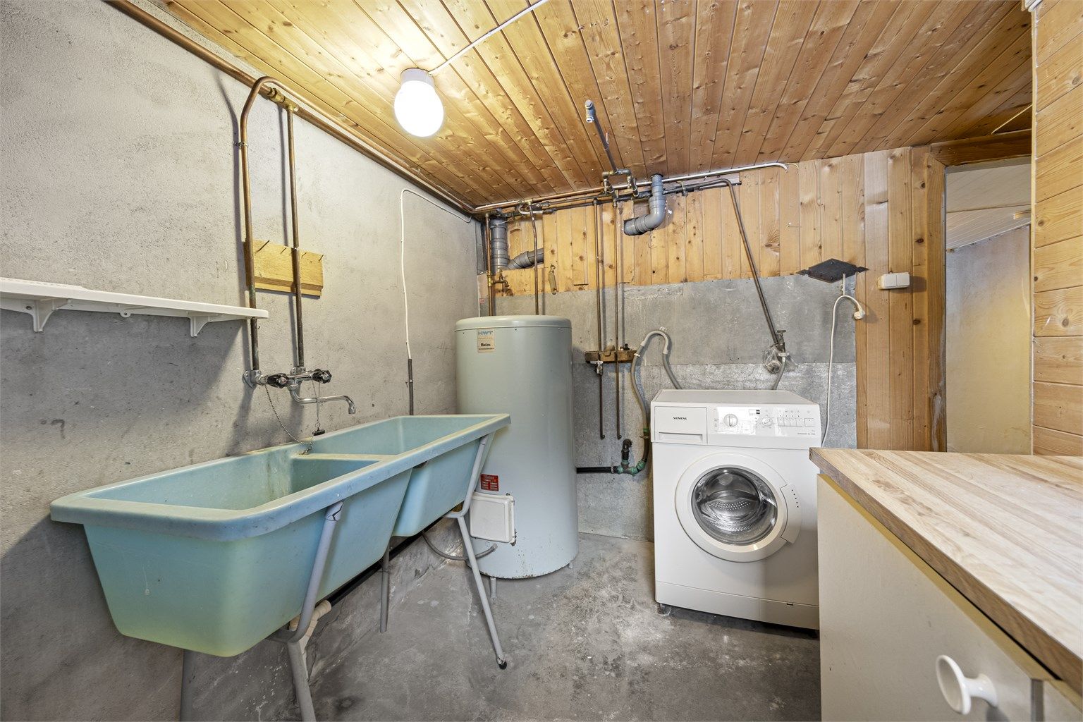 Vaskerom med opplegg for vaskemaskin, utslagsvask og varmtvannsbereder.