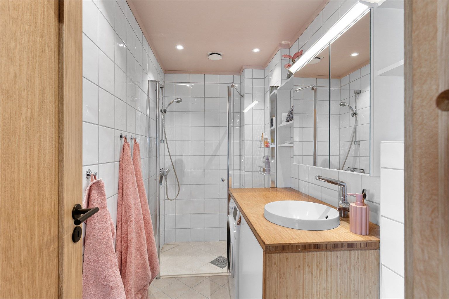 Badet har en moderne innredning med himling av malte plater, innfelte downlights og fliser med elektrisk gulvvarme
