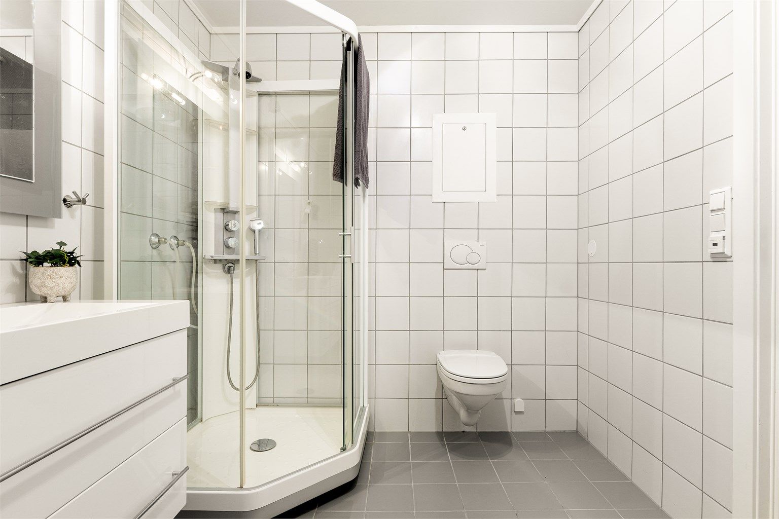 Innredet med vegghengt servantinnredning, speil med lys, dusjkabinett og toalett. Det er opplegg for vaskemaskin.