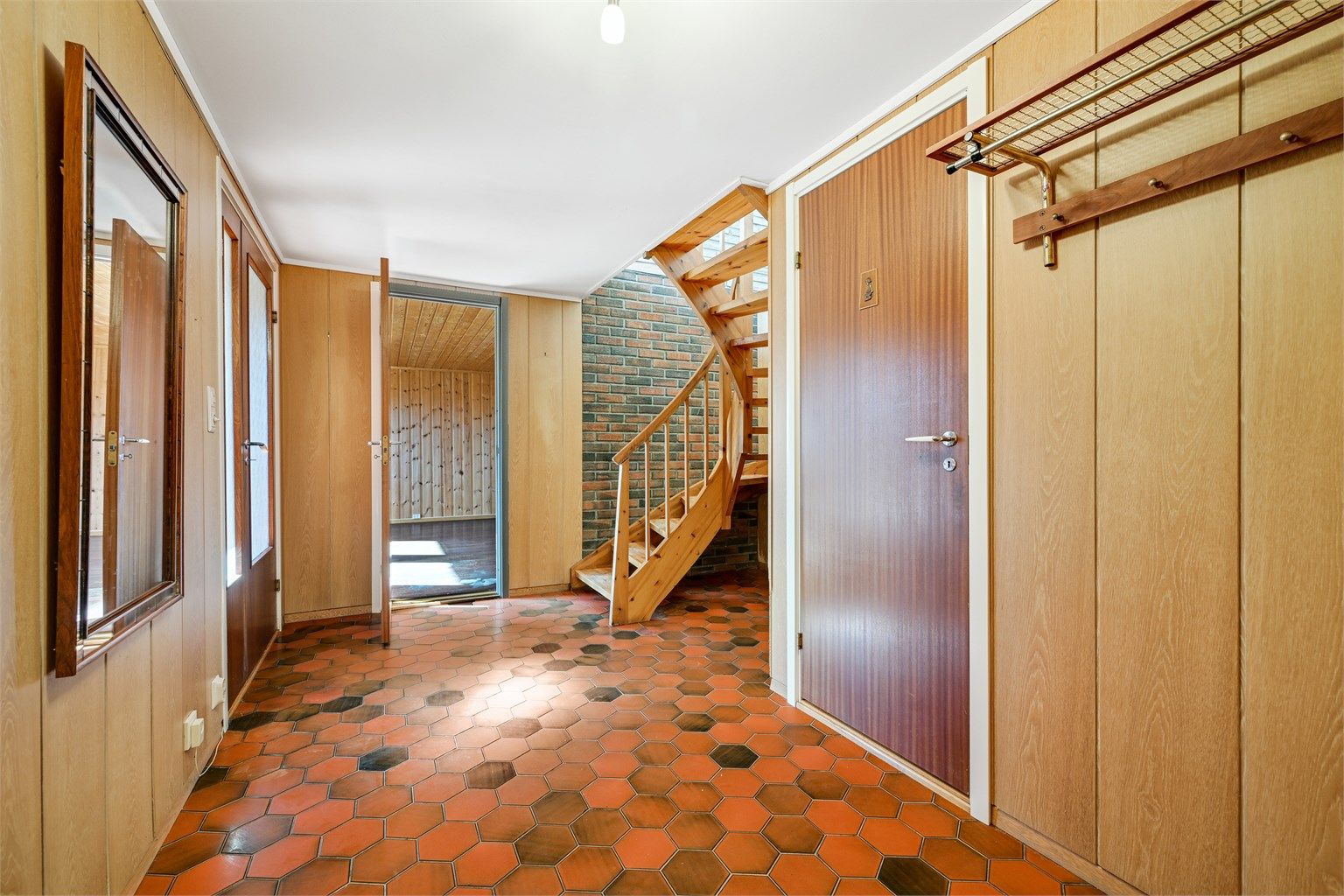 Vindfanget og hallen i sokkeletasjen ønsker velkommen inn. Trappen forbinder de to etasjene.