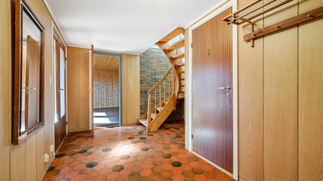 Vindfanget og hallen i sokkeletasjen ønsker velkommen inn. Trappen forbinder de to etasjene.