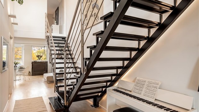 Innvendig trapp i stål og stein forbinder etasjene og slipper lyset gjennom rommene. Trappen fremstår som et naturlig blikkfang i boligen.