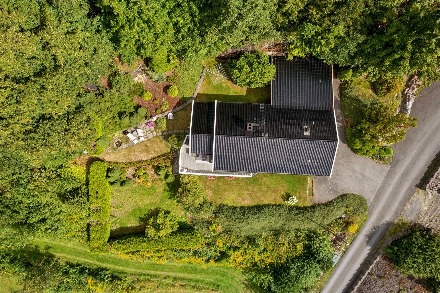 Eiendommen sett fra luften, med opparbeidet hage og carport.