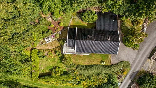 Eiendommen sett fra luften, med opparbeidet hage og carport.