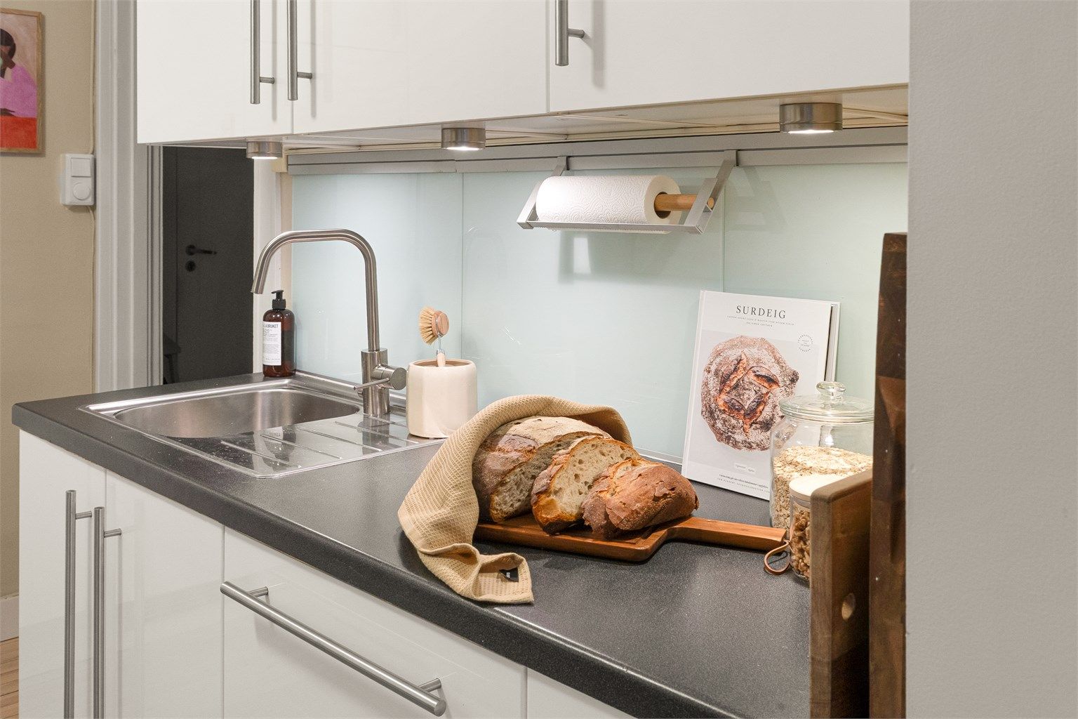 Kjøkkenet er i tillegg utstyrt med integrert induksjonstopp, stekeovn, oppvaskmaskin og kjøleskap, samt kullfilterventilator over koketoppen.