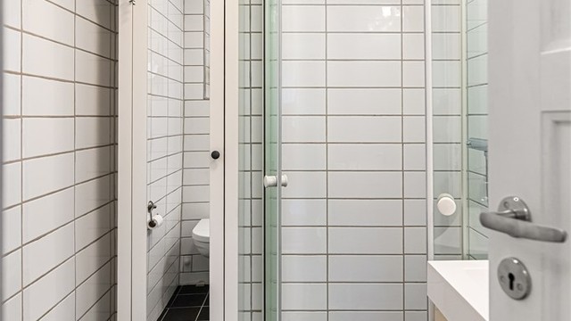 Badet har fliser på gulv og vegger, elektriske varmekabler og dusjhjørne.
