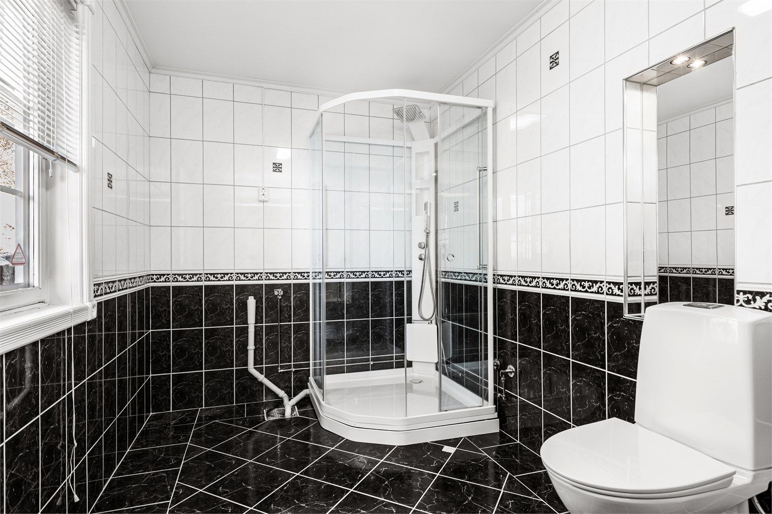 Badet har flislagt gulv med gulvvarme, dusjkabinett og opplegg for vaskemaskin.