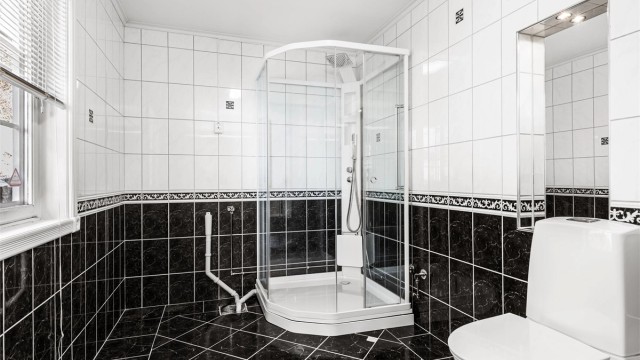 Badet har flislagt gulv med gulvvarme, dusjkabinett og opplegg for vaskemaskin.