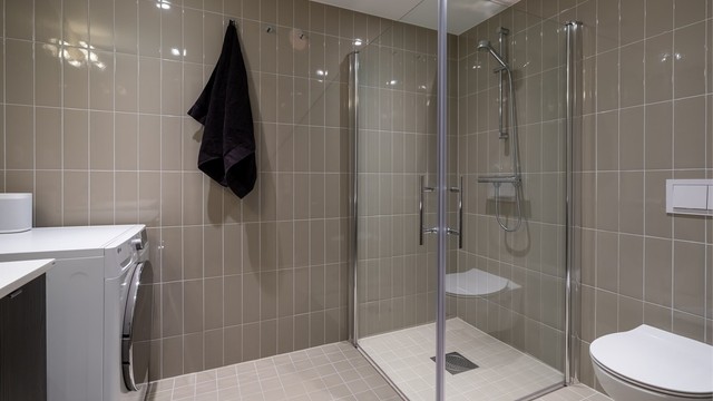 Videre er det vegghengt toalett og dusjhjørne med innfellbare glassdører. Baderommet har også opplegg for vaskemaskin og plass til tørketormmel.