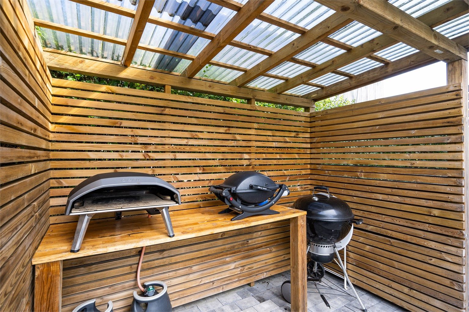 Frittstående, takoverbygd grillområde på den nordvendte uteplassen.