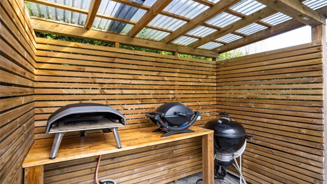 Frittstående, takoverbygd grillområde på den nordvendte uteplassen.
