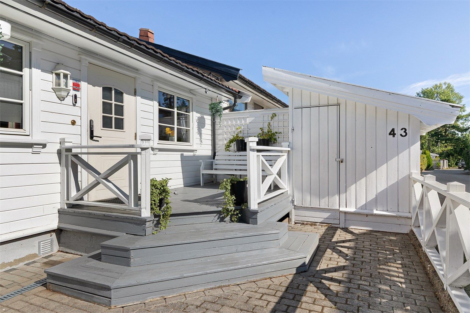 Steinlagt gårdsplass med en hyggelig adkomst og bod utenfor døren