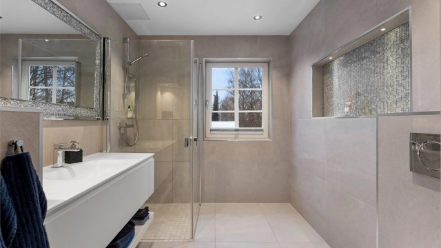 Lekkert baderom fra 2020 med fliser på gulv med gulvvarme, fliser på vegger og nedsenket himling med downlights