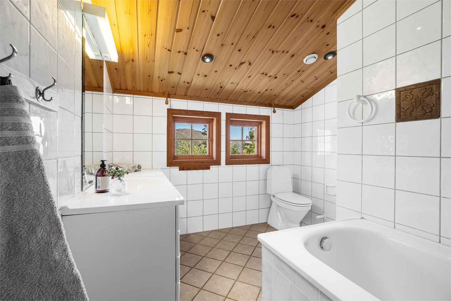 Baderommet har badekar, toalett og to vinduer som tilfører naturlig dagslys.