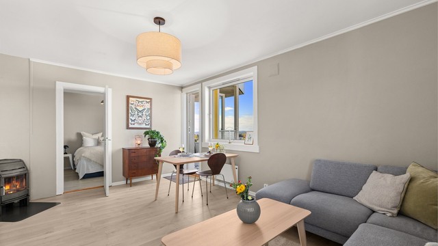 Den romslige stuen har plass til både spisebord og en komfortabel sofagruppe, mens peisovnen bidrar med både varme og ekstra hygge gjennom året.