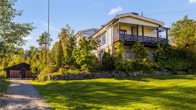 Huset ligger idyllisk til, omkranset av åkerlandskap og skog. Her er det stille, vakkert og fredelig. Panelet på gavlveggen er malt etter at bildet ble tatt.