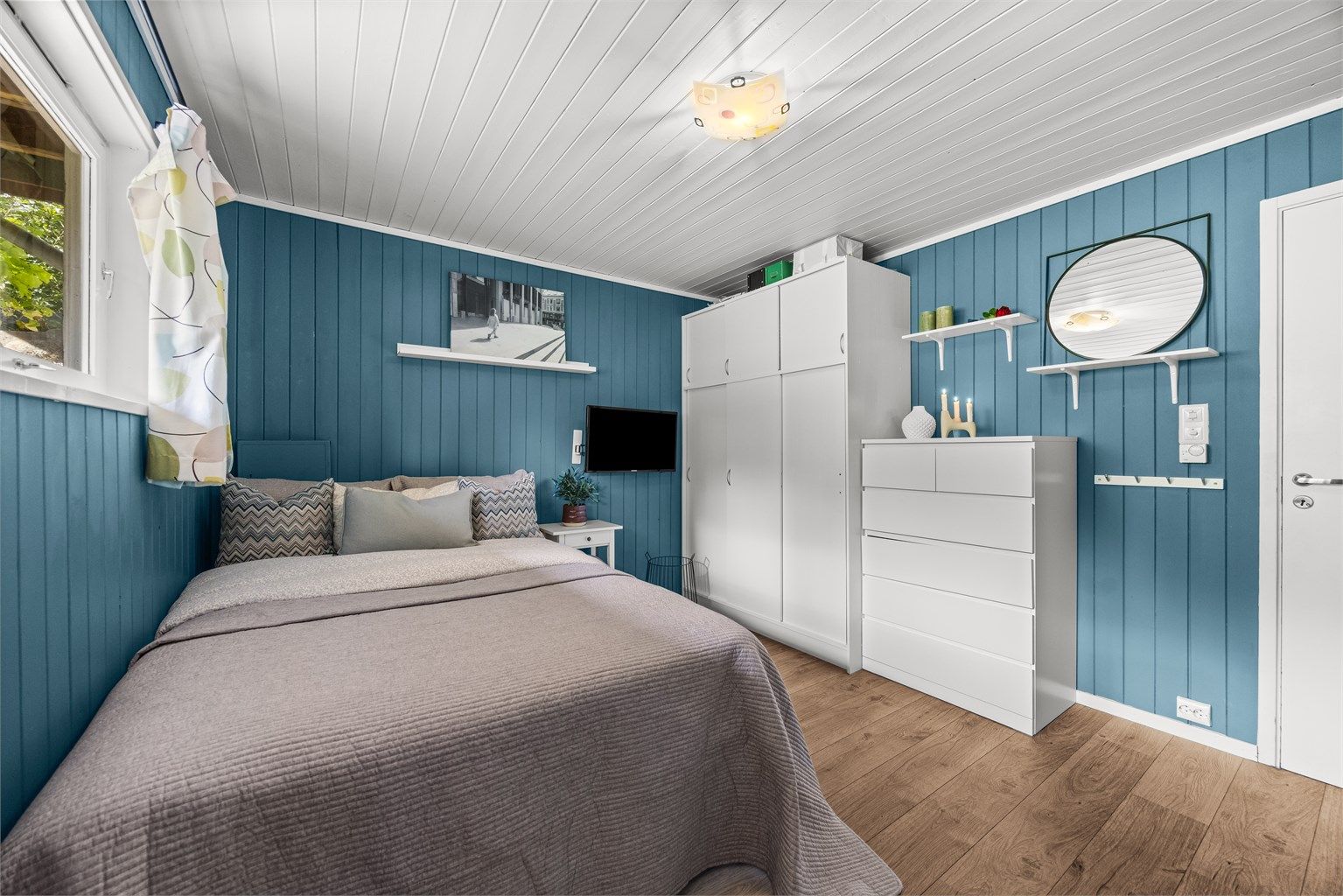 Rommet har malt panel på veggene og laminat på gulvet.