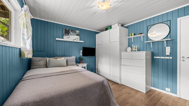 Rommet har malt panel på veggene og laminat på gulvet.