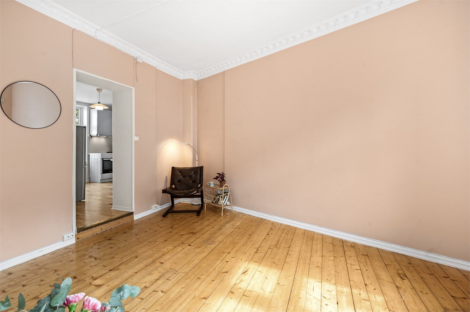 Åpen og stor stue med klassiske detaljer som flott stukkatur, rosett og tregulv.