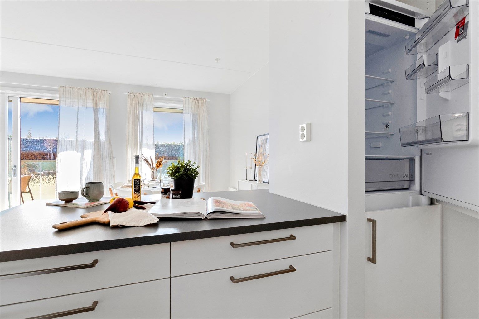 Den åpne løsningen mellom kjøkken og stue skaper en sosial og luftig atmosfære.