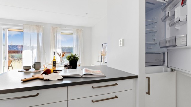 Den åpne løsningen mellom kjøkken og stue skaper en sosial og luftig atmosfære.