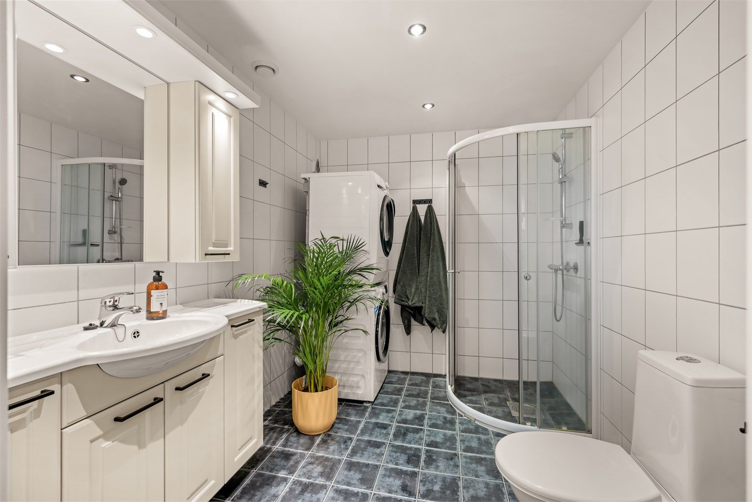 Badet er innredet med dusjhjørne, servantmøbel og har opplegg for vaskemaskin.