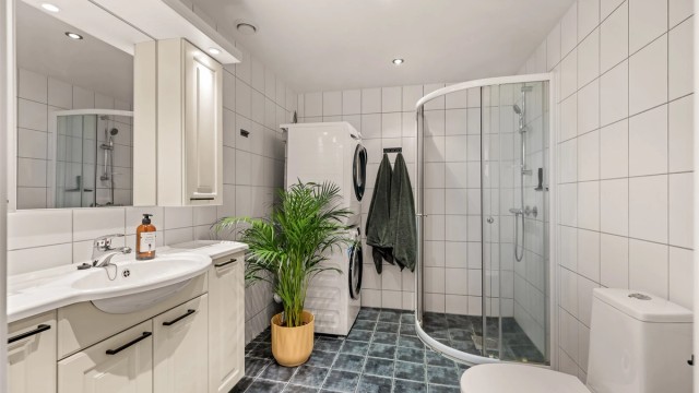 Badet er innredet med dusjhjørne, servantmøbel og har opplegg for vaskemaskin.