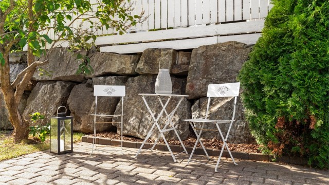 Forstøtningsmurer av naturstein rammer inn utearealet og gir en lun sitteplass.