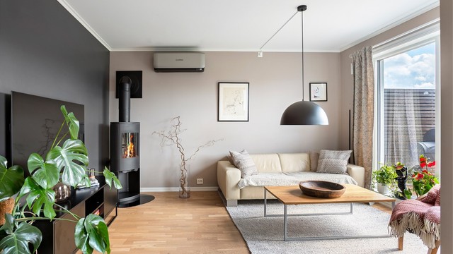 Leiligheten har en åpen stue- og kjøkkenløsning med både vedovn og varmepumpe for effektiv oppvarming.