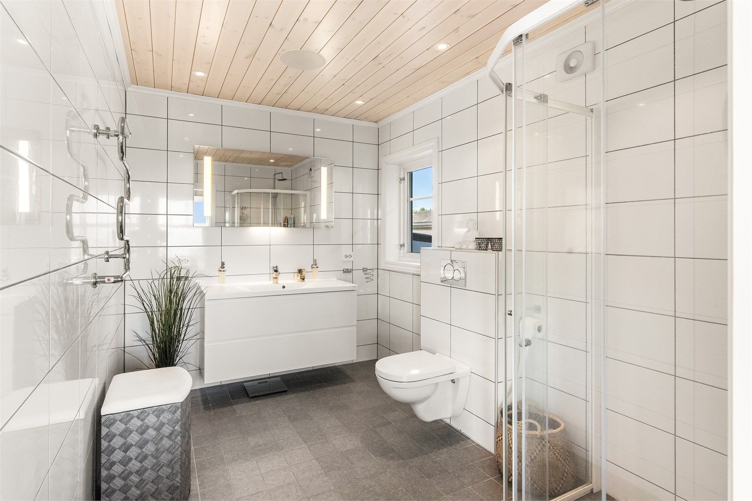 Badet til hovedsoverommet er lekkert innredet med dusjhjørne, vegghengt toalett, servant i innredning og håndkletørker