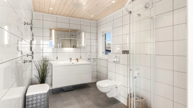 Badet til hovedsoverommet er lekkert innredet med dusjhjørne, vegghengt toalett, servant i innredning og håndkletørker