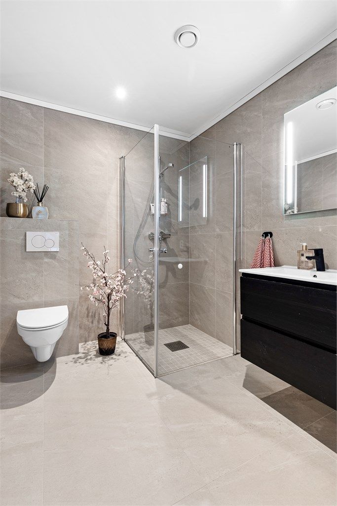 Speil med integrert belysning over servant. Stikkontakt på vegg. Nedsenket dusjsone med innfellbare glassdører. Dusjarmatur tilkoblet hånddusj.