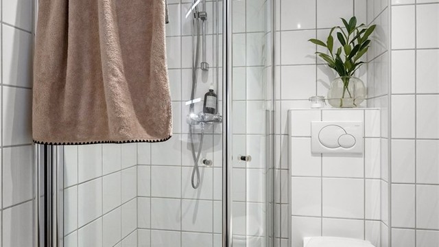 Badet er utstyrt med vegghengt toalett, dusjhjørne med innfellbar glassdører