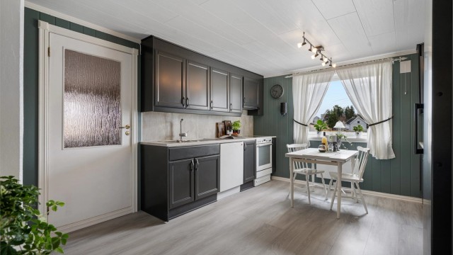 Laminert benkeplate med skyllekum og oppvaskkum med ettgreps armatur, og platekledning over benkeplate.