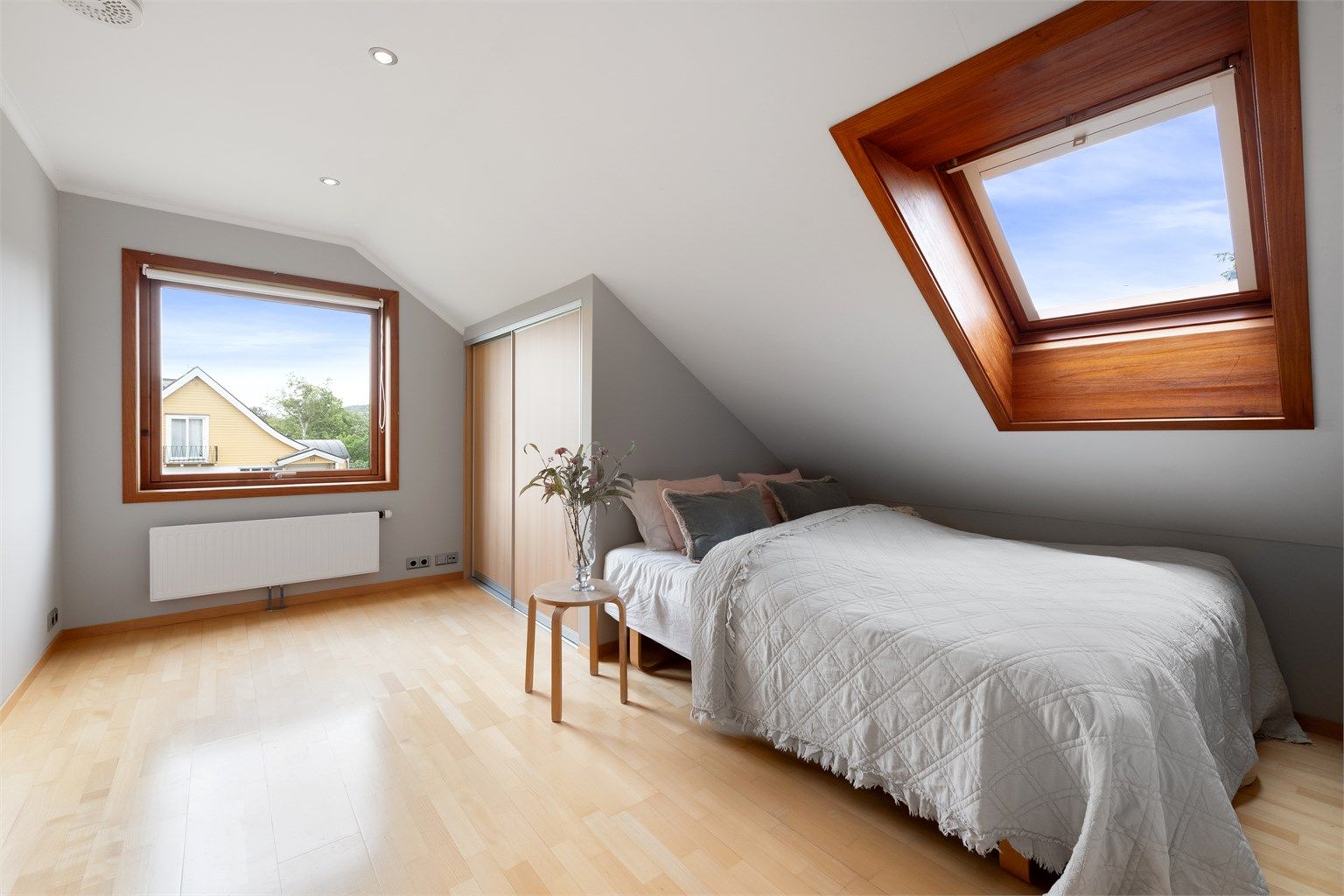 Soverom med overlysvindu, skyvedørsgarderobe og parkettgulv.
