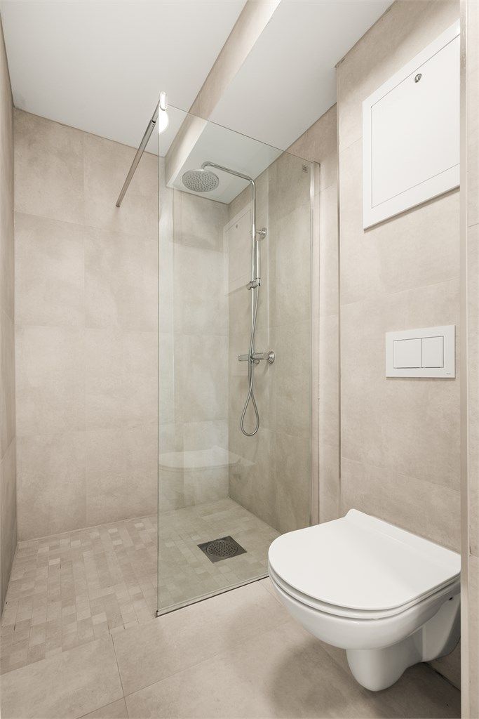 Dusjhjørne med moderne flisvalg. Badet har mekanisk avtrekk.