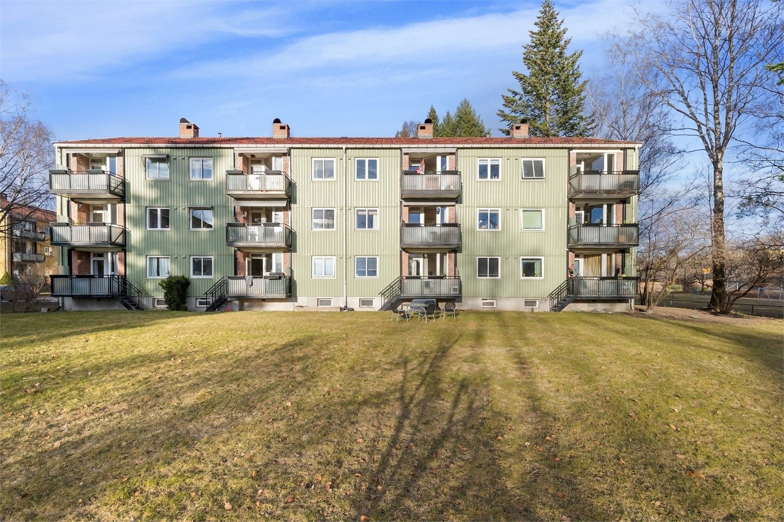 Sameiet har velholdte fellesarealer med gressplen, trær og beplantning.