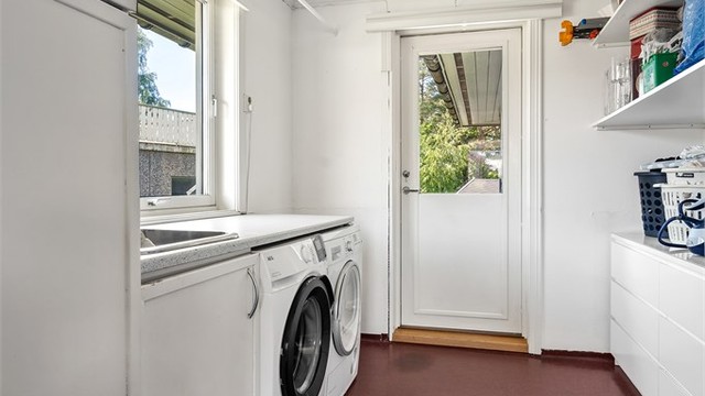 Praktisk vaskerom med opplegg for vaskemaskin og egen utgang til terrasse og hagen