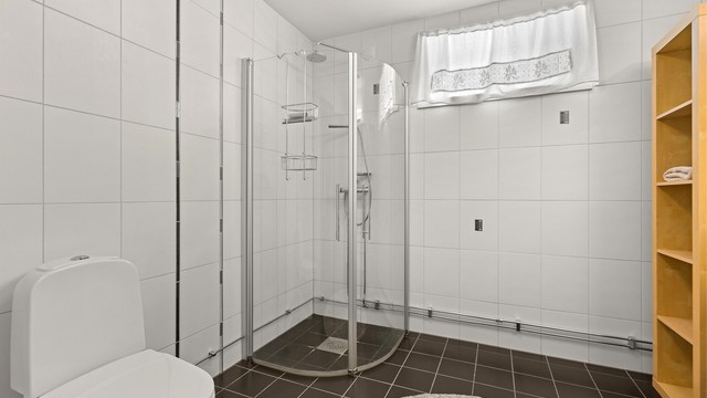 Rommet er utstyrt med dusjhjørne med innfellbare glassdører og regndusj.