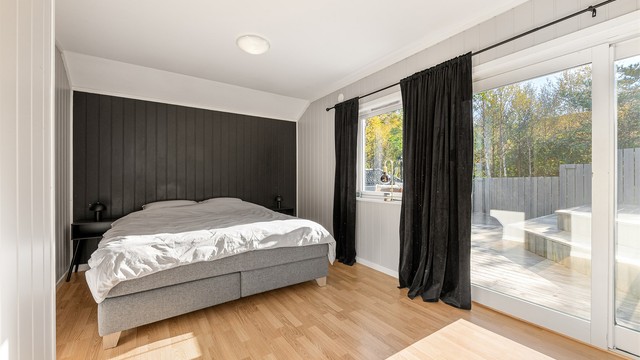 Soverom i 1. etasje med skyvedør i tre og direkte utgang til terrassen.