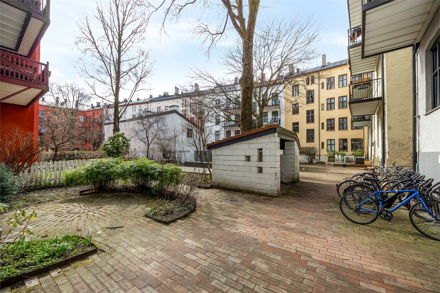 Hyggelig bakgård bestående av diverse beplantning, prydbusker og steinbelagte arealer bestående av gangbaner.