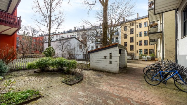 Hyggelig bakgård bestående av diverse beplantning, prydbusker og steinbelagte arealer bestående av gangbaner.