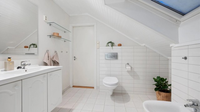 Badet er videre utstyrt med servantskap med speil, dusjhjørne, bidé og vegghengt toalett.