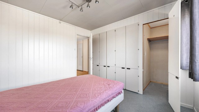 En hel vegg med innebygde skap gir rikelig med garderobeplass.