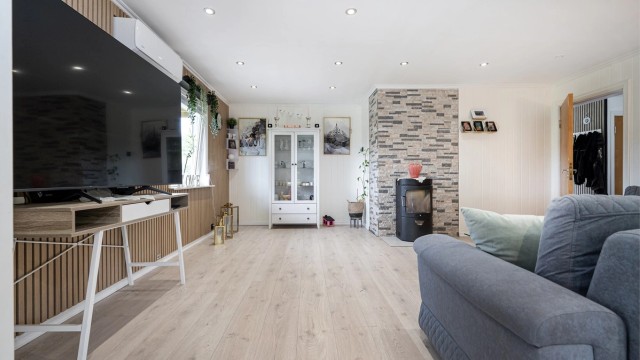 Stuen har god plass til sofagruppe og er utstyrt med et ildsted fra byggeåret.