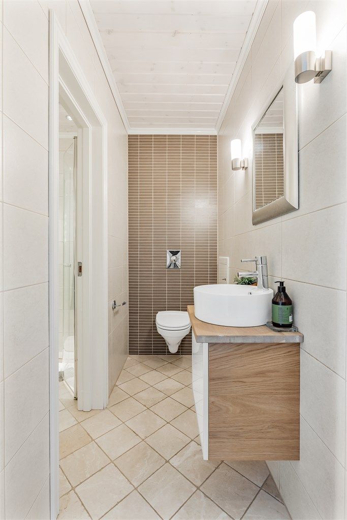 Toalettrom med flislagt gulv med varme. Vegghengt servantinnredning. Vegghengt toalett. Mekanisk avtrekk med ventil i vegg.