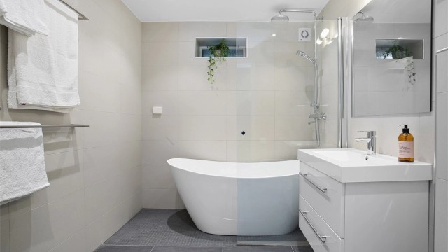 Badet er innredet med frittstående badekar og dusjhjørne med regndusj.